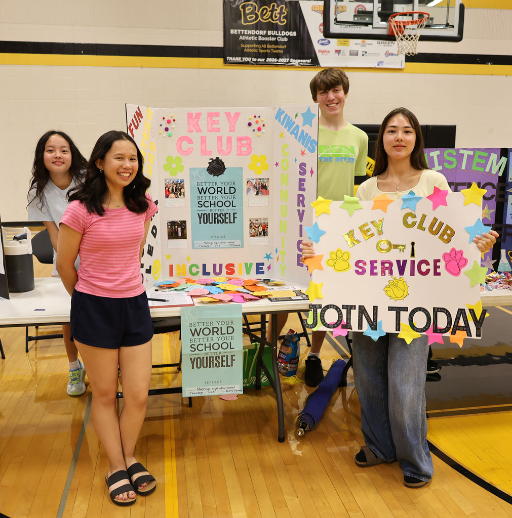 Four Key Club members with color signs about key club