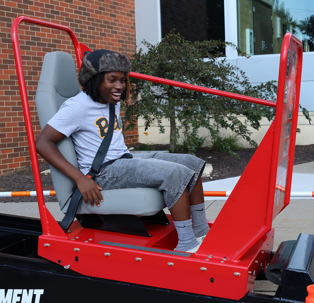 A young man with a huge smile at the bottom of the Bettendorf Police seat belt convincer