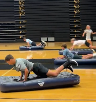 Students diving onto air matresses to move them down the gym