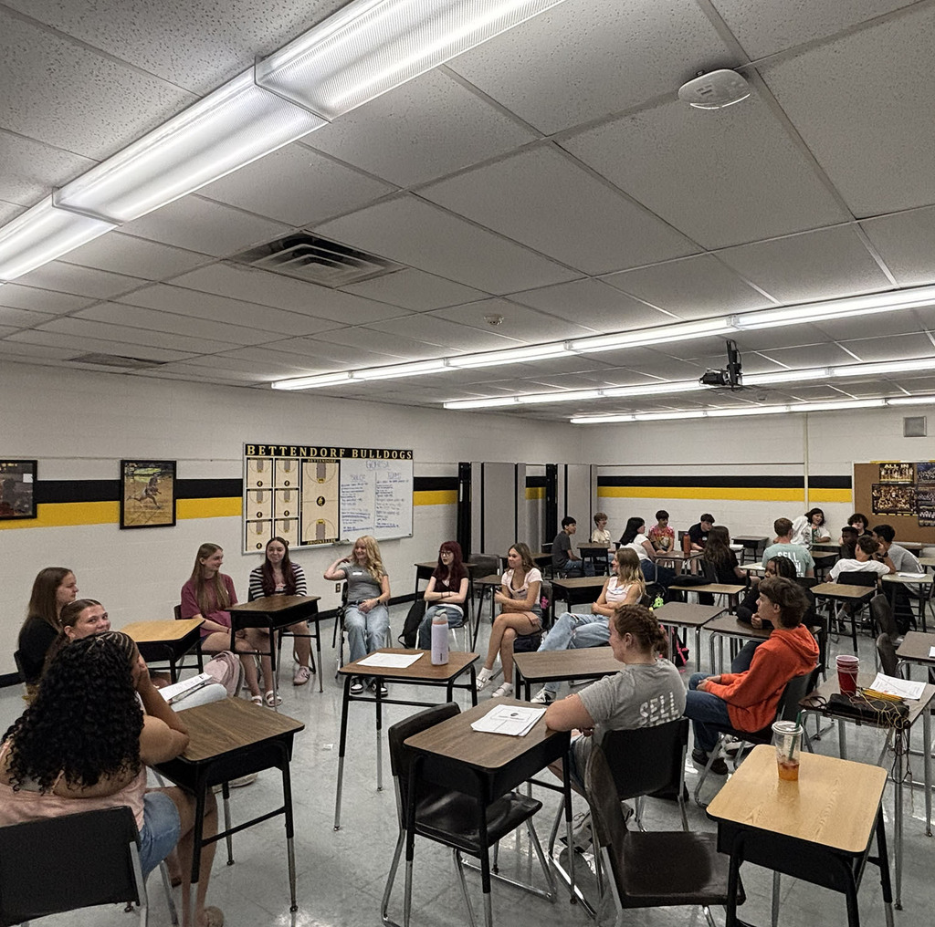 Students in a circle in a classroom working on small group activities.