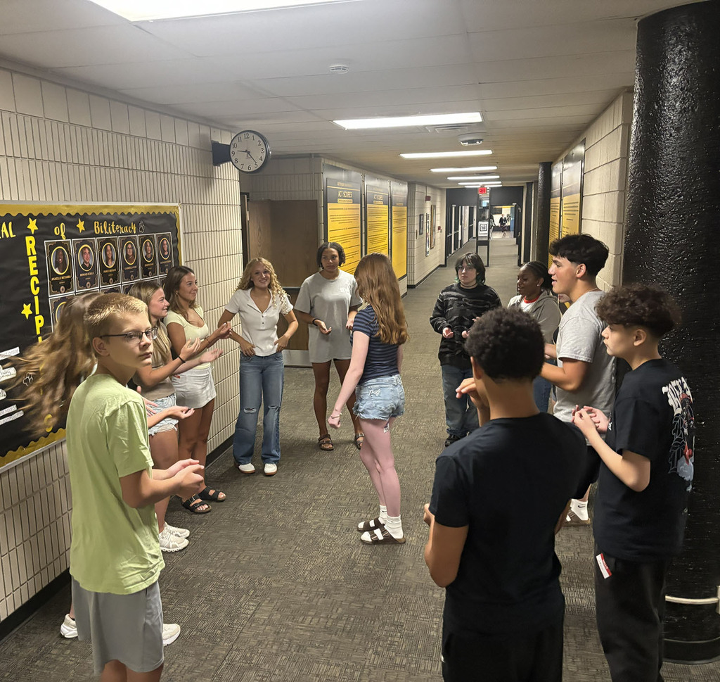 Students working together on small group activities to get to know each other in the hallway