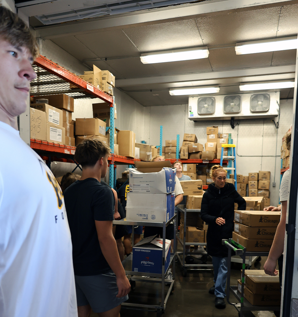 Football players moving food from the freezer.