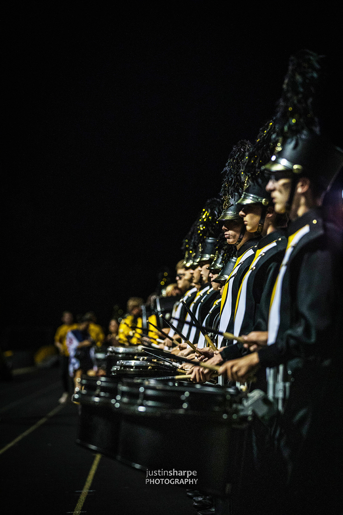 Drummer lined u p tightly and drumming during a night football game