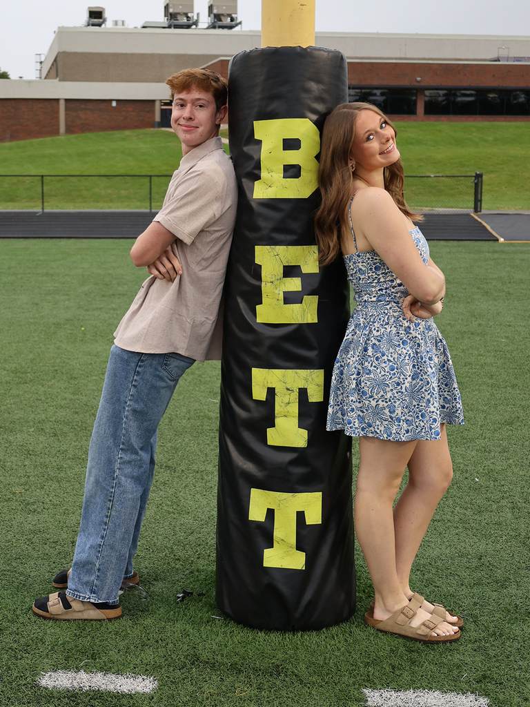 John Chandler and Carolyn Halbur leaning on the goal post with BETT stencil