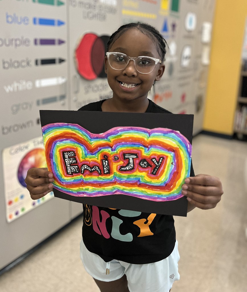 Emi-Joy smiling with her art design in a rainbow of colors