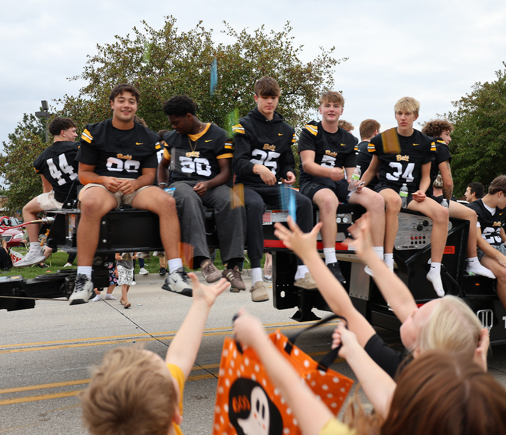Kids holding out their arms from candy from the football team 