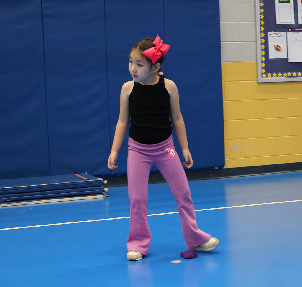 A young girl passes the bag between her feet