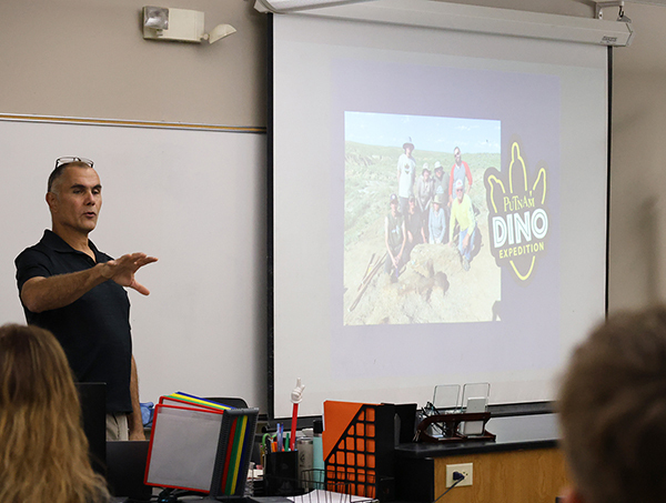 Dr. Ericksen with an image of the excavation crew including meneber from the Putnam museum staff.