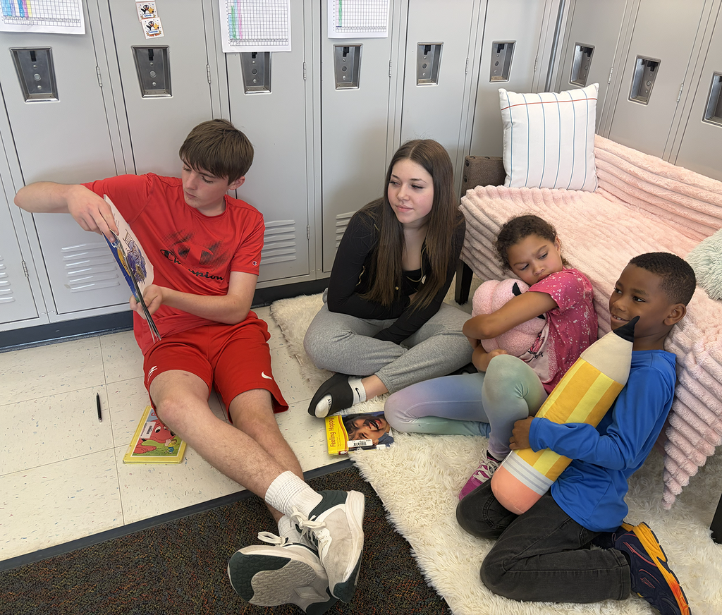 Two HS students sitting with two elementary and reading