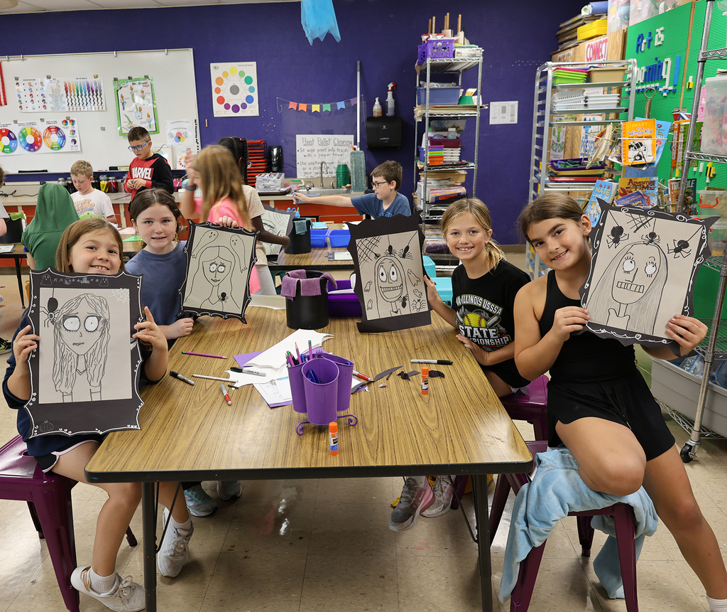 A table of girls showing off their spooky self portraits with big eyes, ghosts, and spiders