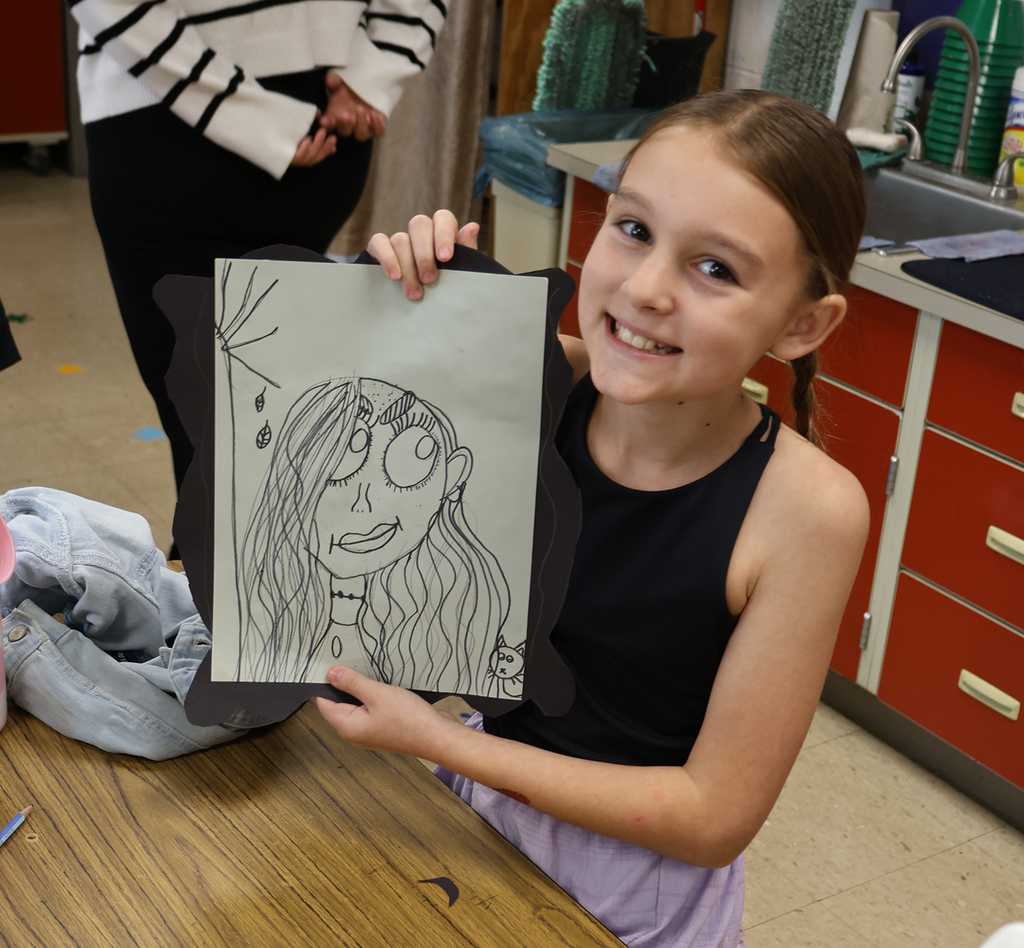 A girl smiling as she shows her portrait with a fall tree and a girl with long hair and big eyes