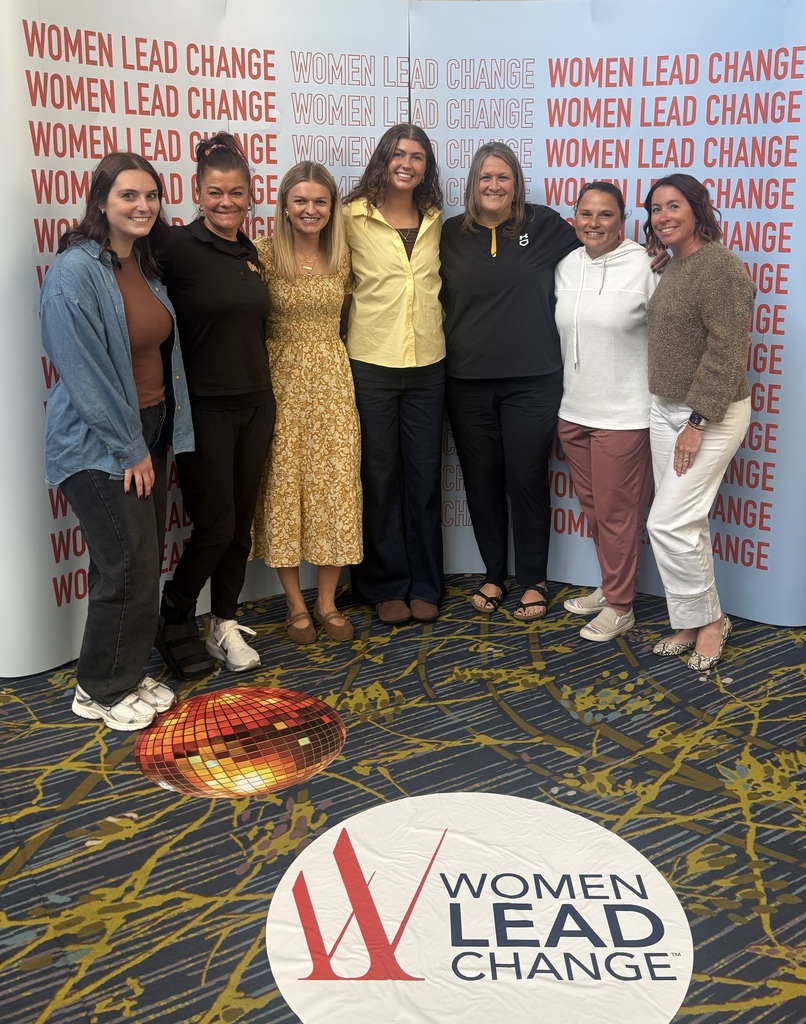 A group of Bettendorf schools staff in front of a Women Lead Change backdrop