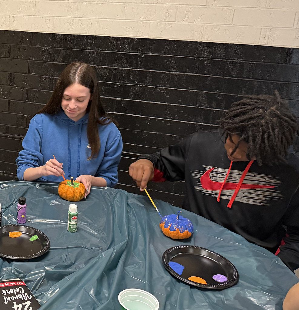 Two student busy painting their pumkins