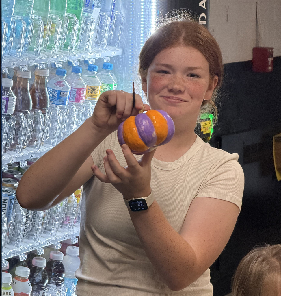 A girl showing off her beautiful purple and orange pumkin