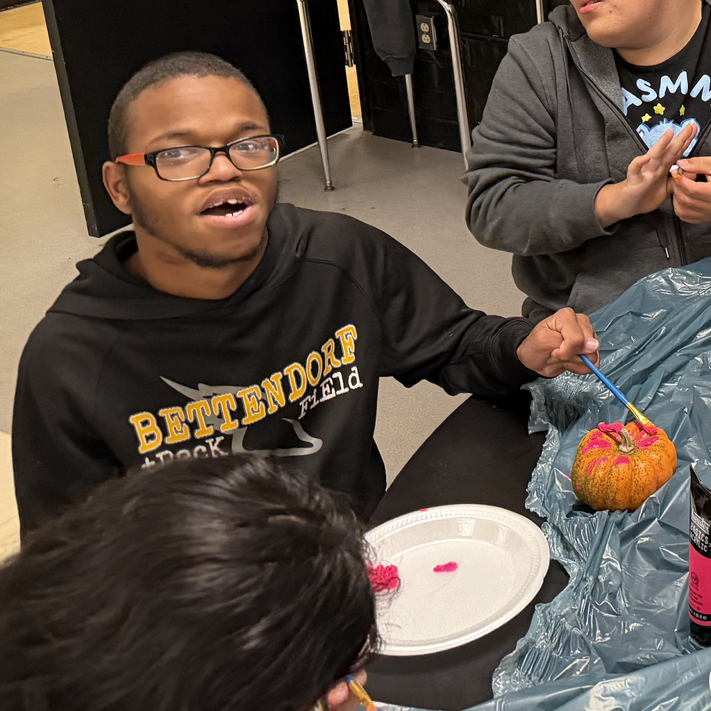 A student working on painting his pumpkin
