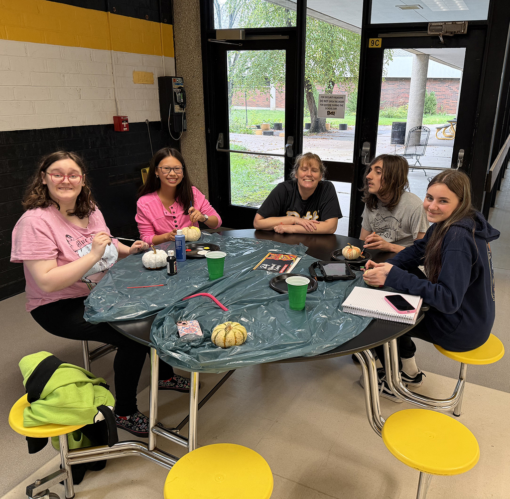 A table of students painting pumpkins