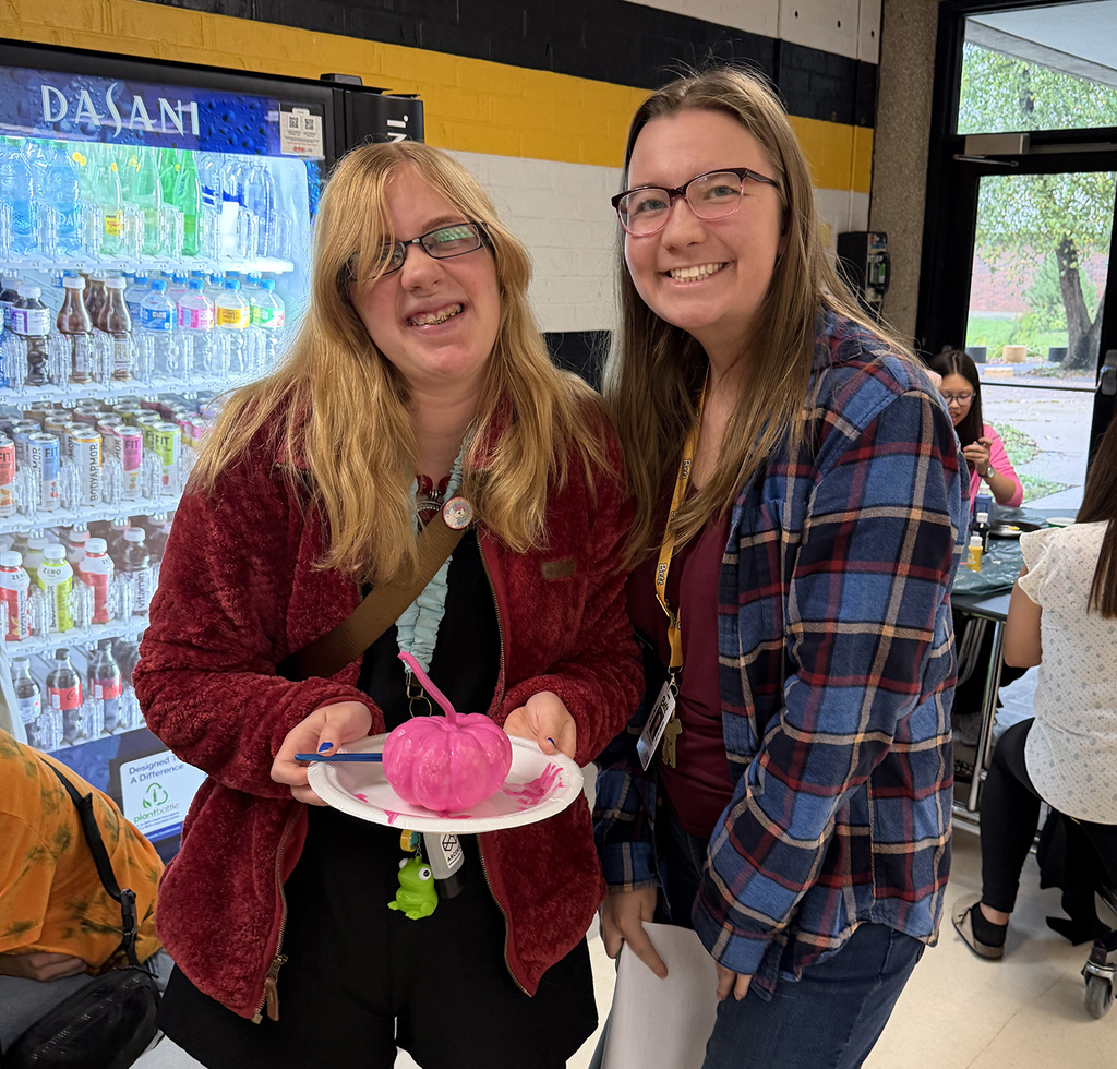 A student showing her pink pumkin with her teacher