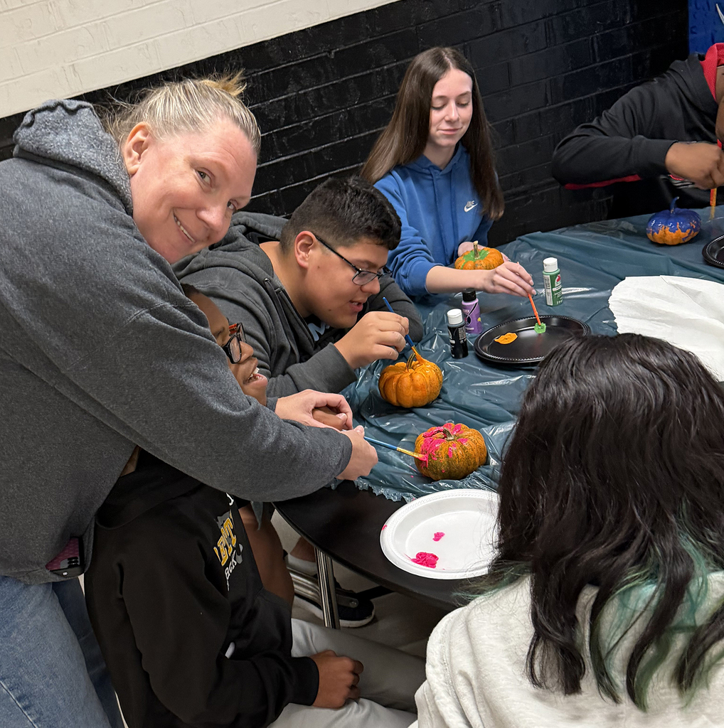 A paraeducator helping a stundet to paint his pumkin
