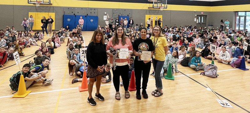 Dr. Morse, Kait Holldorf, Jaque Krause, and Principal Graap in front of students at the Friday assembly