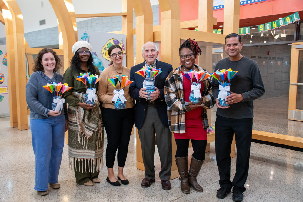 carrie button, shaunte middleton, amanda jesenof, albert penna, jesula saintus, and steve seepersaud hold arrangements of paper flowers while posing for photo at macarthur elementary