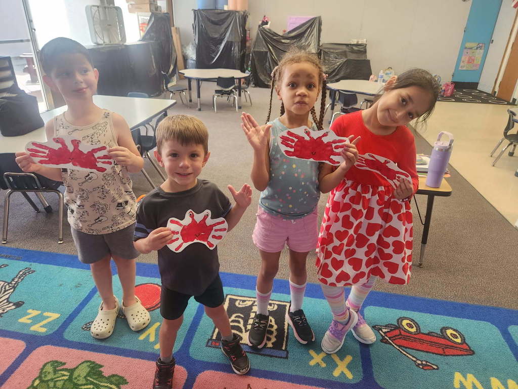 students hold handprint crab artwork at imagination adventure