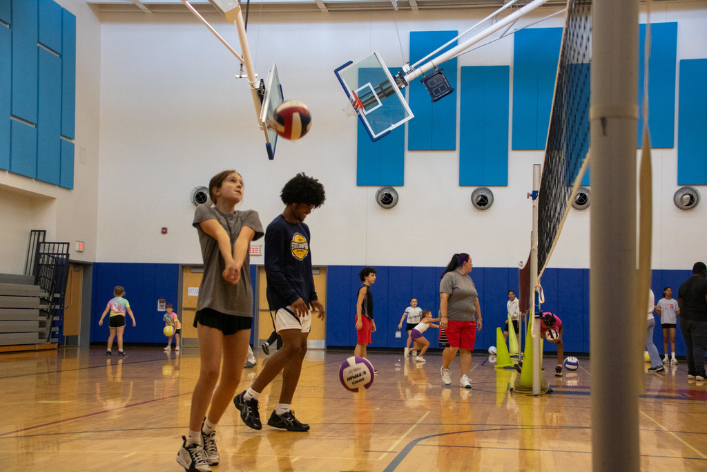 student gets ready to hit volleyball as it comes over the net
