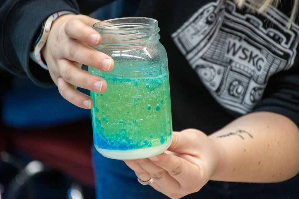 close up of jar with vinegar, oil, and baking soda creating a reaction that looks like a lava lamp