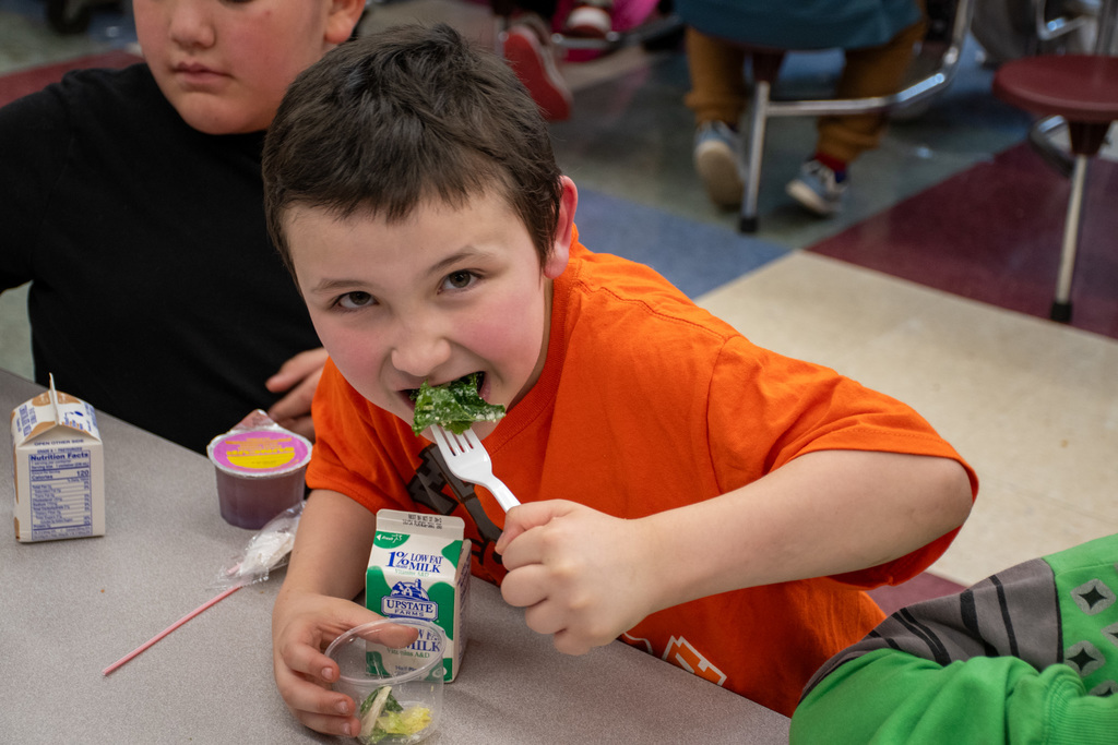 student eats kale romaine caesar salad