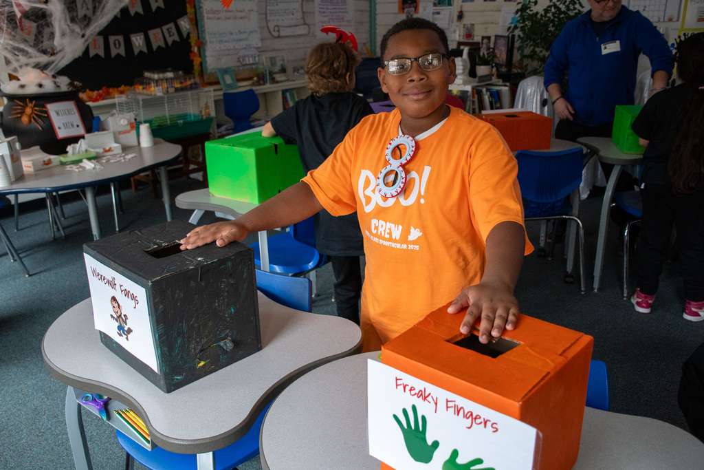 student smiling for camera with sensory boxes