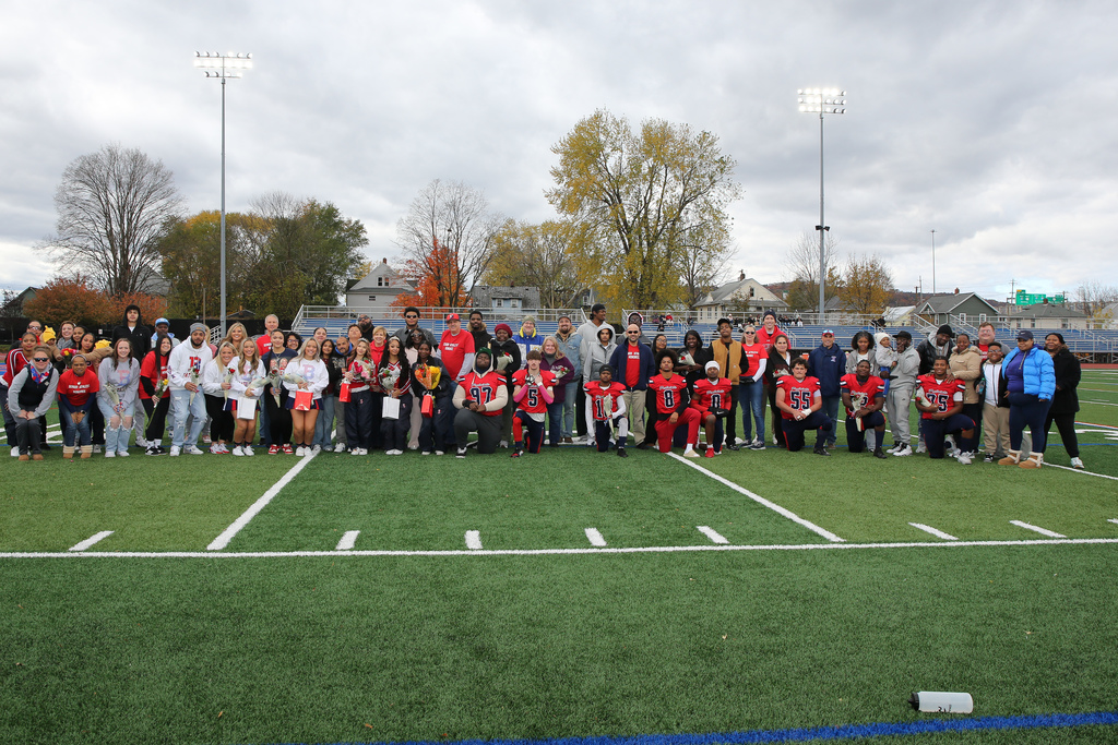 seniors from football and cheer teams pose for photo on football field with their families