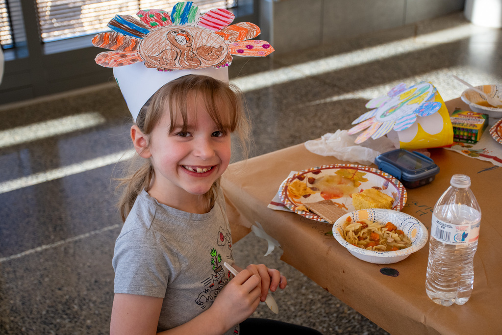 student with thanksgiving hat smiles for camera