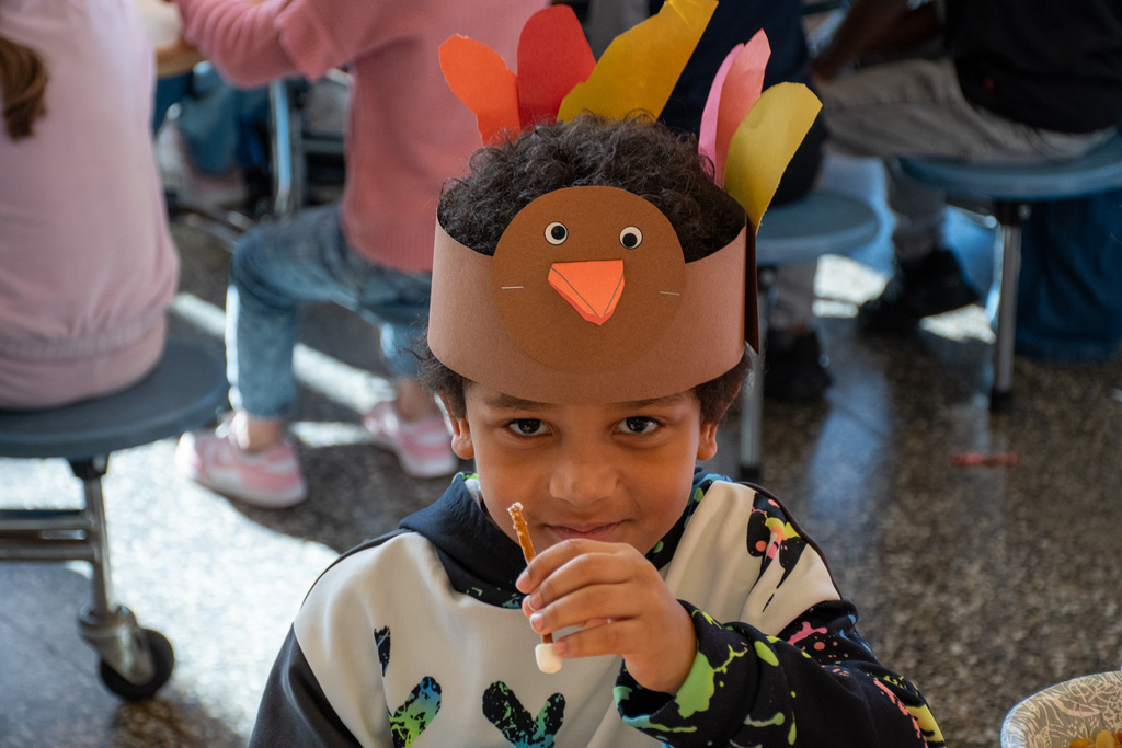 student with thanksgiving hat smiles for camera