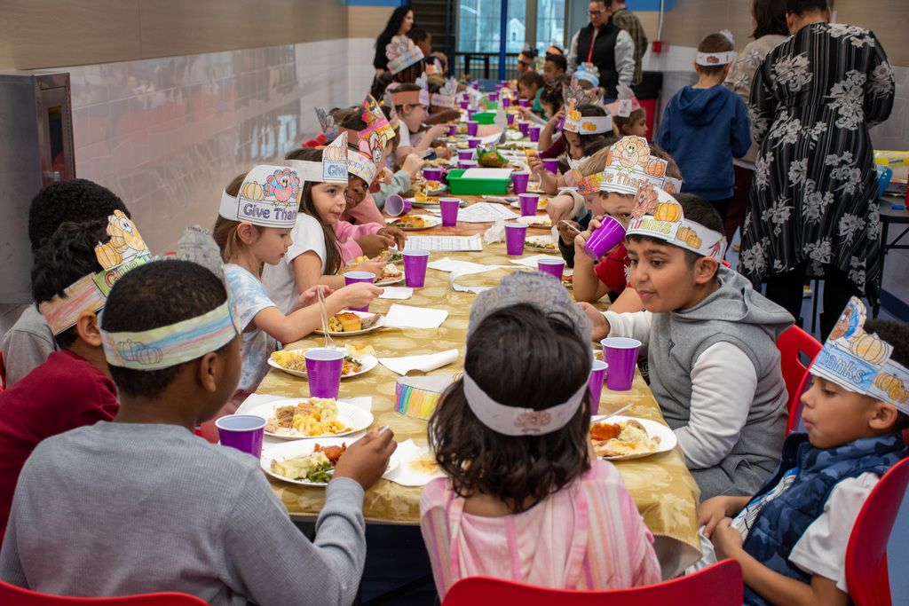 franklin students sit at long table while eating a thanksgiving feast