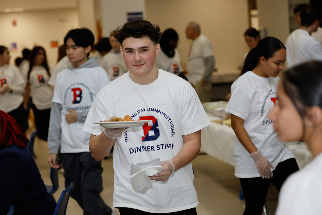 student serves plate of food at thanksgiving dinner