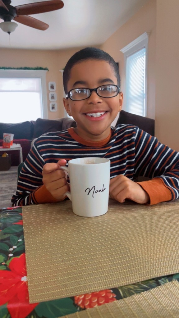 student smiles for camera while drinking hot cocoa