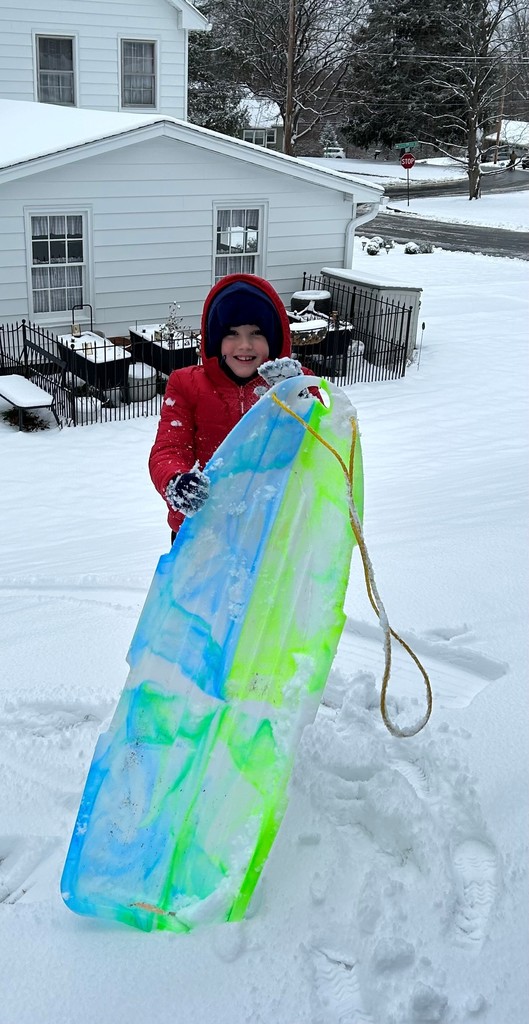 student poses for photo with sled