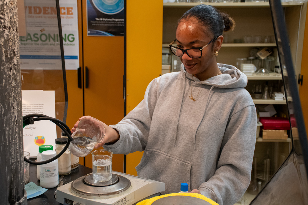 chemistry student pours liquid into beaker