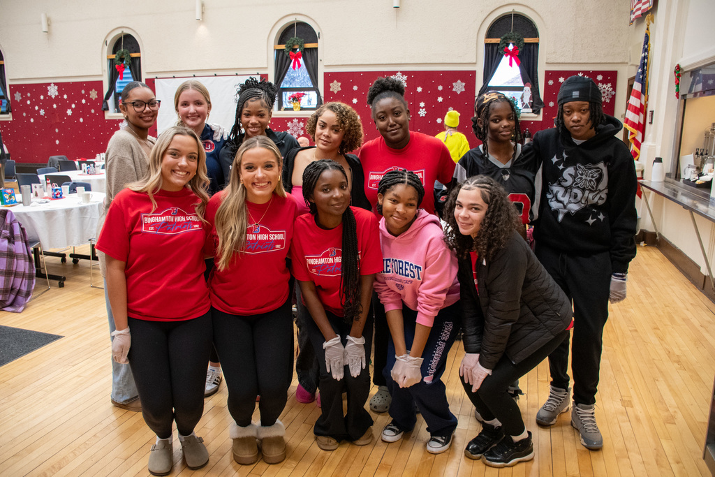 girls basketball players and cheerleaders pose for photo before serving lunch at senior center
