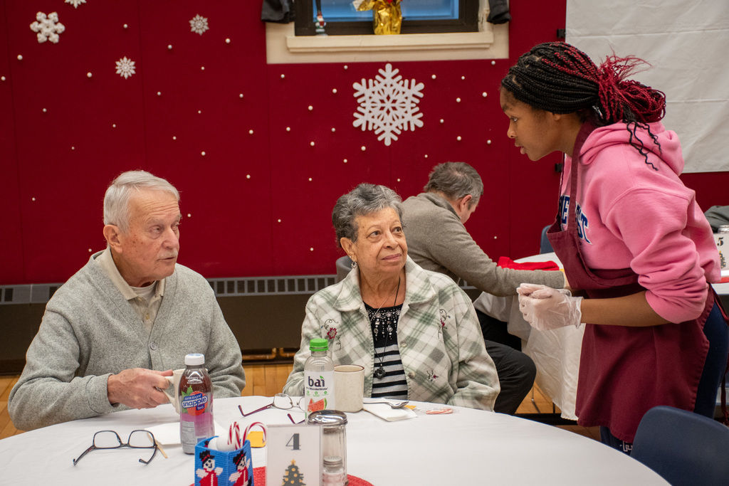 cheerleader takes order from couple sitting at table