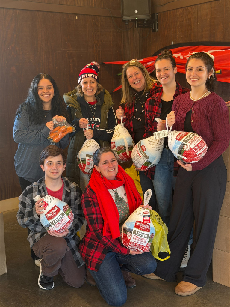 seven people pose for photo holding frozen turkeys