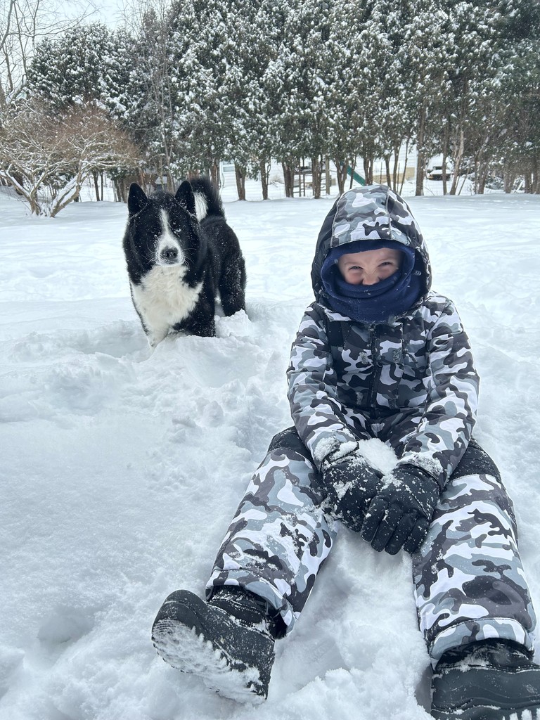 child and dog sitting in snow
