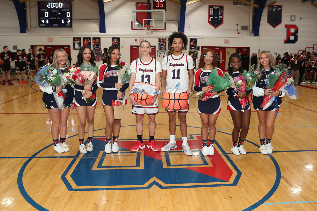 senior cheerleaders and basketball players pose for photo at center court of BHS gym