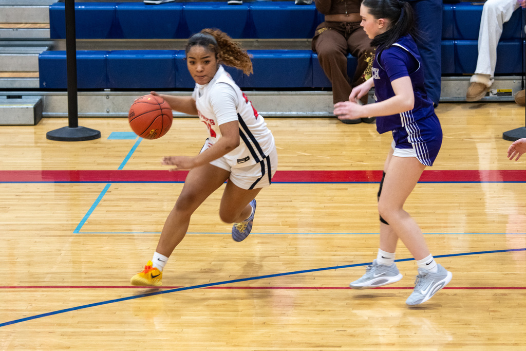 girls jv basketball player dribbles during game against norwich