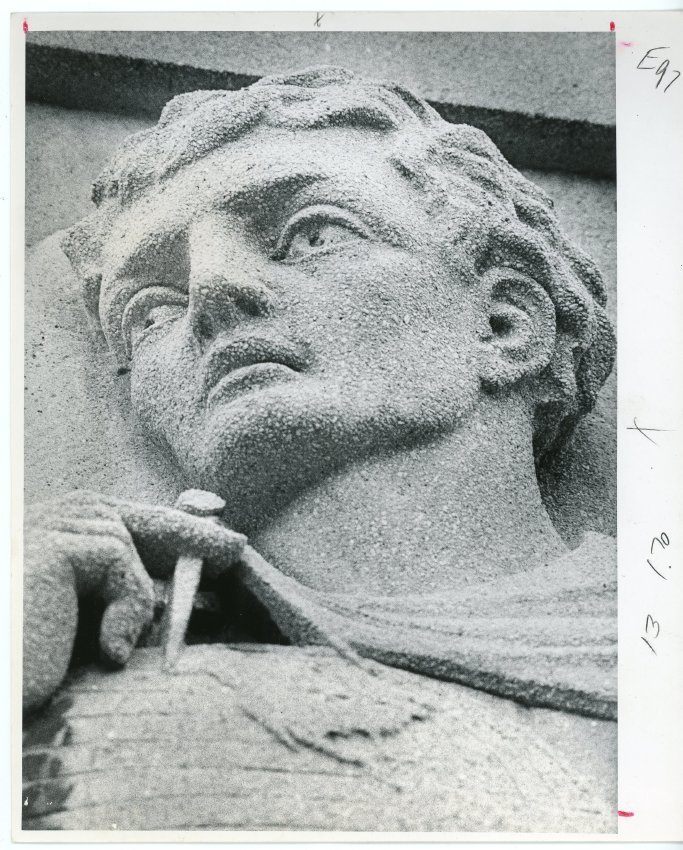 photo from 1931 of the face of man holding globe carved into building