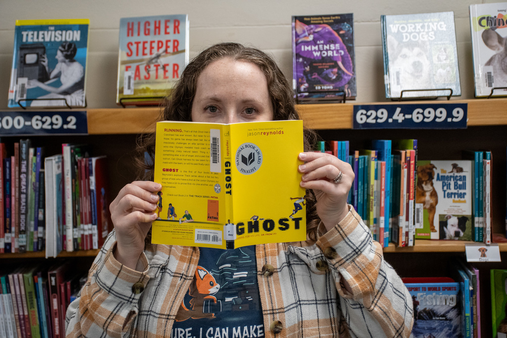 school librarian holds up "ghost" by jason reynolds