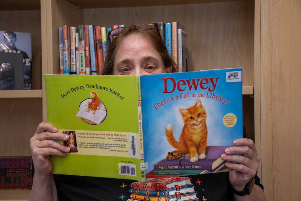 school librarian holds up "Dewey there's a cat in the library!" by vicki myron