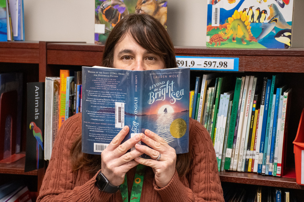 school librarian holds up "beyond the bright sea" by lauren wolk