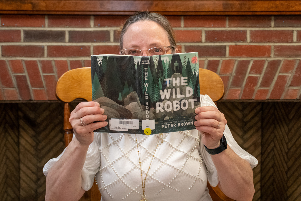 school librarian holds up "the wild robot" by peter brown