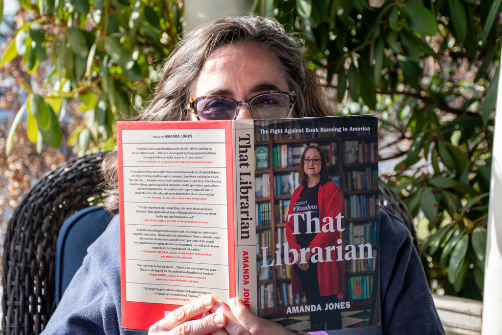 school librarian holds up "that librarian" by amanda jones