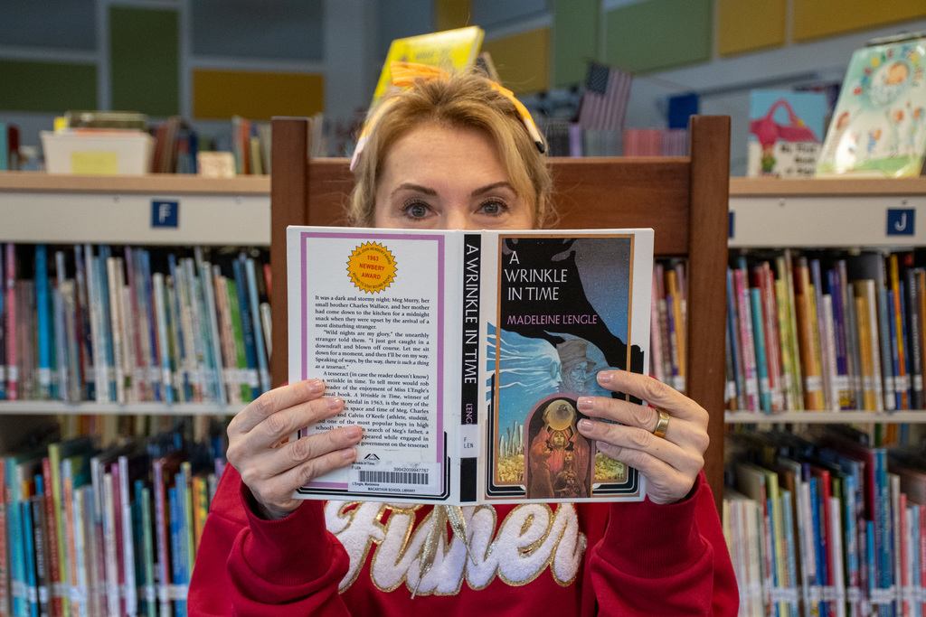 school librarian holds up "a wrinkle in time" by madeleine lengle